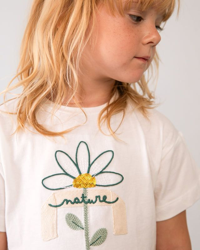 Dettaglio maglietta bambina con fiore ricamato e scritta nature