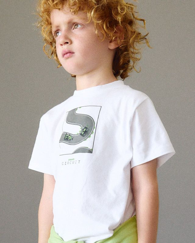 Bambino con T-shirt bianca e pantaloni sportivi in grigio