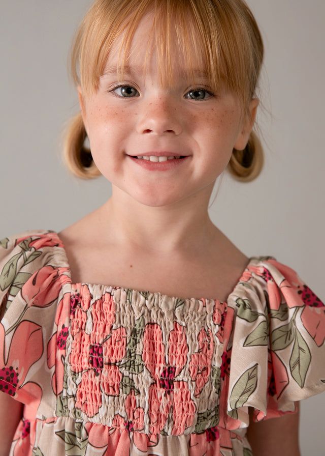 Bambina sorridente con vestito floreale nido d'ape Mayoral
