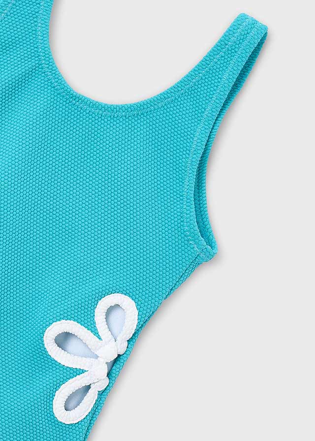 Dettaglio del tessuto del costume da bagno bambina Mayoral celeste con fiore bianco