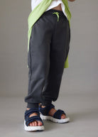 Bambino con pantaloni sportivi in grigio e sandali in blu
